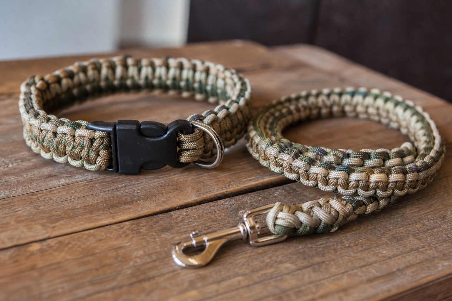 Handmade braided paracord dog collar next to a matching leash on a wooden surface